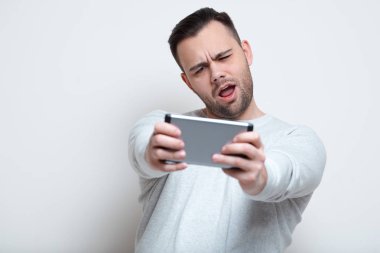 Video oyunları smartphone üzerinde beyaz arka plan üzerinde oynarken mutlu çığlık atan adam