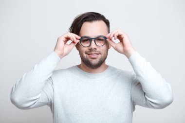 Beyaz arka plan üzerinde mavi gözlük takan genç gülümseyen adam portresi