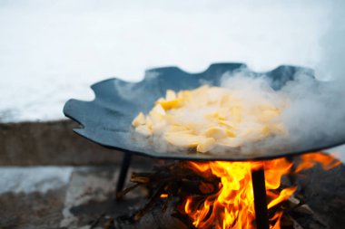 Pişirme ve patates kışında açık ateş üzerinde düz bir tavada karıştırarak