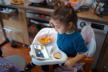 Bebek kız yemek ve seyretmek tablet mutfak Oda
