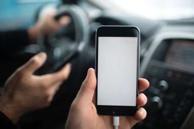 Yakın çekim, el smartphone mockup ile araba Pano arka plan üzerinde tutan adamın.