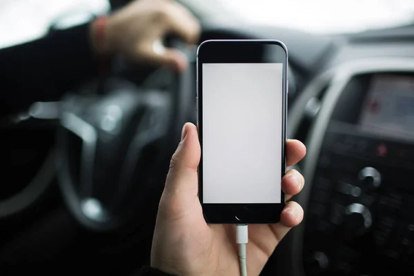 Närbild, handen man håller smartphone med mockup på bakgrund av bilens instrumentbräda. — Stockfoto