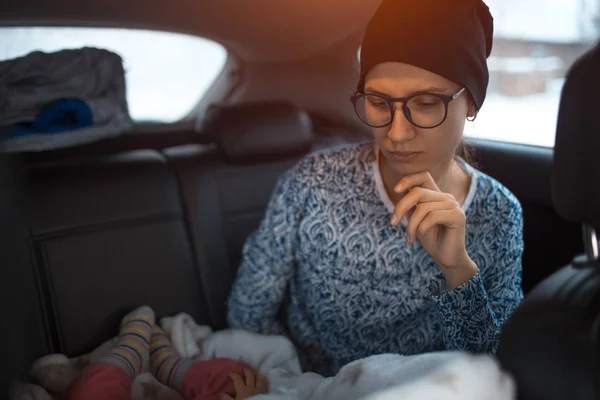 Young mother looks on his sleeping baby in the car. — Stock Photo, Image