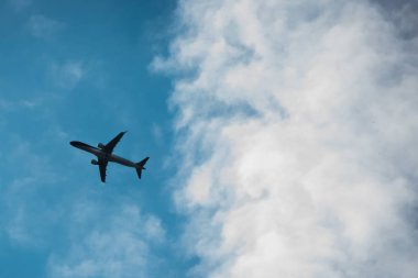 Gökyüzünde uçan uçak silueti, alttan görünüm.