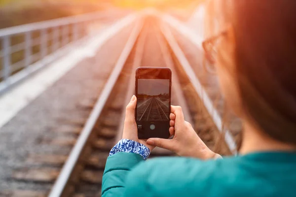 Dívka s smartphone v rukou fotografování železnice. — Stock fotografie