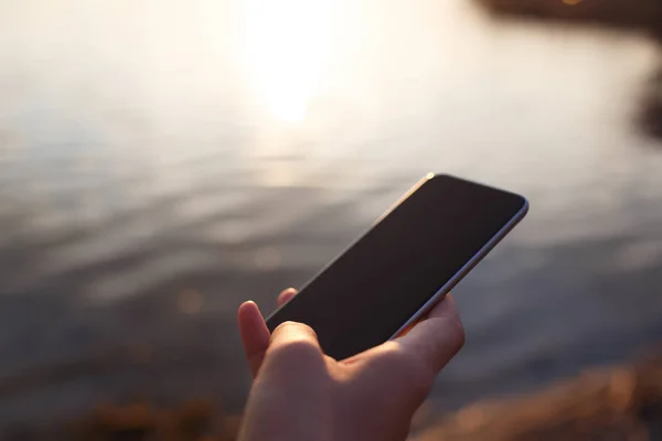 Mantener el teléfono inteligente en la mano sobre el fondo del atardecer . —  Fotos de Stock