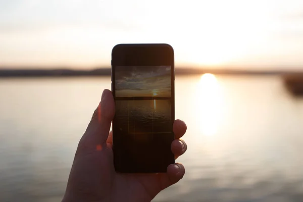 Mužská ruka držící telefon Smartphone a fotografování slunce. — Stock fotografie