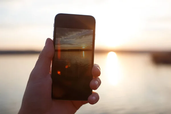 Man handholding smartphone en het nemen van de foto van zonsondergang. — Stockfoto