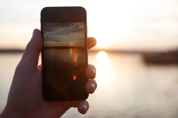 Mužská ruka držící telefon Smartphone a fotografování slunce. — Stock fotografie