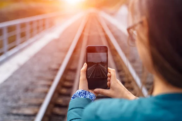 スマートフォンを保持し、写真の鉄道を取る若い女の子. — ストック写真