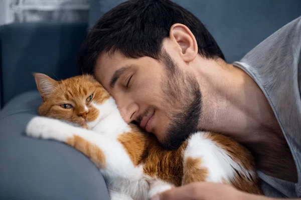 Спящий молодой человек и красная белая кошка . — стоковое фото