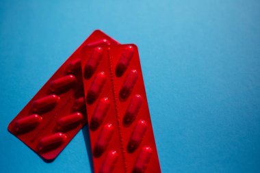 İlaç hapları kapsüller, mavi üzerinde kırmızı paket.