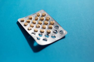 Mavi arka planda kalp şeklinde ilaç tabletler.