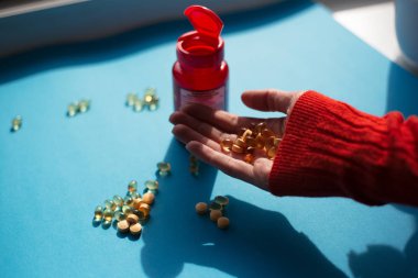 Mavi arka plan üzerinde vitamin ilaç hapları alarak.