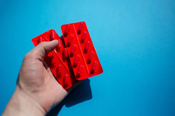 Entrega de pastillas para medicamentos cápsulas, paquete rojo sobre azul . — Foto de Stock