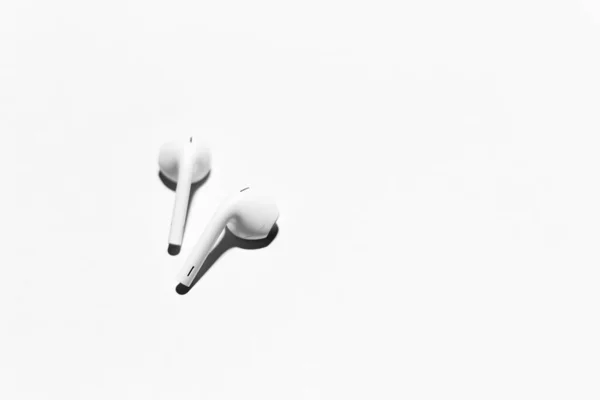 Beyaz kablosuz kulaklıklara yakın plan, beyaz arka planda izole edilmiş..