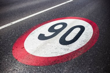 Asfalt yolda 90 km / saat hız sınırı işareti.