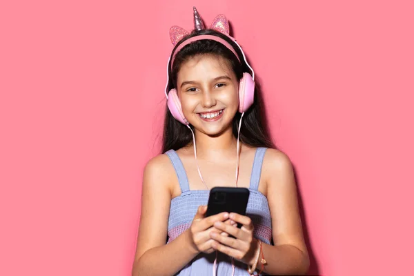 Studio Portret Szczęśliwej Dziewczynki Trzymającej Smartfona Rękach Posługującej Się Słuchawkami — Zdjęcie stockowe