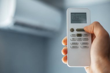 Erkek eli, klimanın uzaktan kumandasını elinde tutuyor..