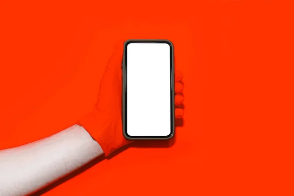 Zbliżenie Męskiej Dłoni Czerwonej Rękawiczce Trzymającej Smartfona Makietą Czerwonym Tle — Zdjęcie stockowe