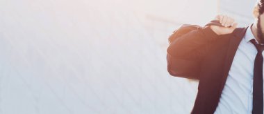 Elinde evrak çantası olan takım elbiseli bir iş adamı. Kopya alanı olan mavi gökdelen penceresinin panoramik arkaplanı. İş konsepti.