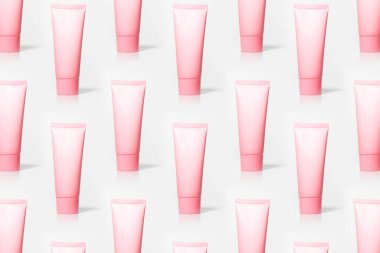 Beyaz arka planda izole edilmiş pastel pembe krem tüpleri..