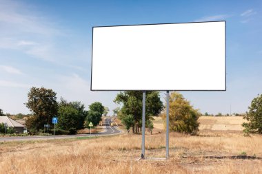 Yol ve köyün yakınındaki reklam afişi için boş ilan panosu. Mavi gökyüzünün ve güzel doğanın arka planı.