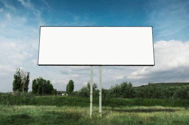 Mavi gökyüzünün arka planında yeşil alanda reklam afişi için boş reklam panosu.