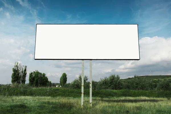 青い空の緑のフィールドの一般的な背景に広告ポスターのための空の看板 — ストック写真