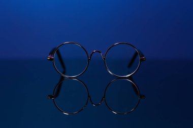 Cam masadan yansıyan yuvarlak bardakları yakın çekim. Renkli hayalet mavisinin arkaplanı.