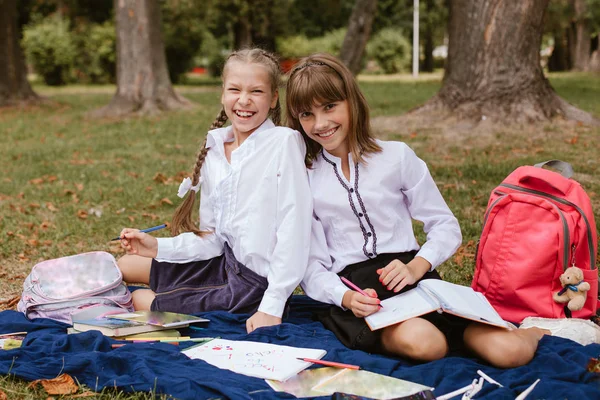 学校に戻れ自然の中で宿題をしている小学生たち 女子高生は公園で楽しんでいます — ストック写真