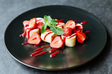 Güzel tatlı çilek ve siyah bir plaka üzerinde nane ile