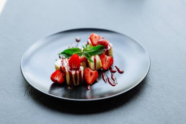 Güzel tatlı çilek ve siyah bir plaka üzerinde nane ile