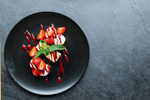 Güzel tatlı çilek ve siyah bir plaka üzerinde nane ile