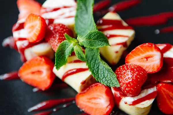 Güzel tatlı çilek ve siyah bir plaka üzerinde nane ile