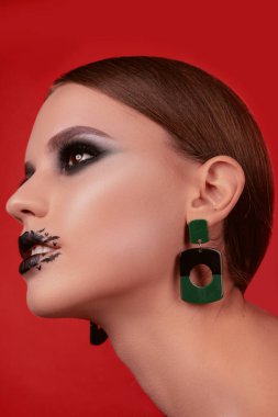 Güzellik makyaj kırmızı bir arka plan üzerinde Cadılar Bayramı tarzında güzel bir kızla portreleri