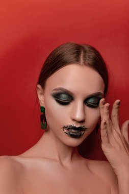 Güzellik makyaj kırmızı bir arka plan üzerinde Cadılar Bayramı tarzında güzel bir kızla portreleri