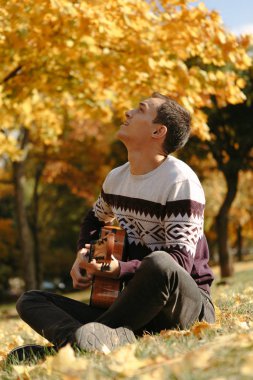 Yakışıklı olan sonbahar parkta gitar ile