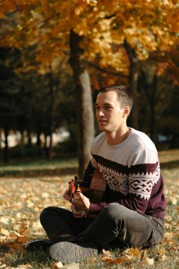 Yakışıklı olan sonbahar parkta gitar ile