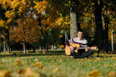 Yakışıklı olan sonbahar parkta gitar ile