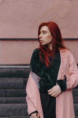 Kızıl saçlı güzel ve şık bir kız şehirde yürür ve saçları rüzgarda olduğunu