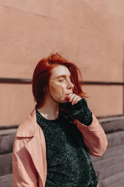 Kızıl saçlı güzel ve şık bir kız şehirde yürür ve saçları rüzgarda olduğunu