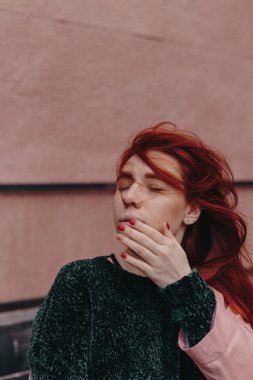 Kızıl saçlı güzel ve şık bir kız şehirde yürür ve saçları rüzgarda olduğunu
