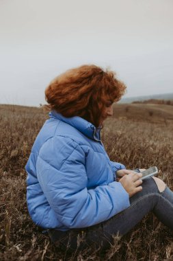 Kızıl saçlı güzel bir kız seyahat geniş alanlar ve çayırlar, termos çay içiyor ve sahne hayran.
