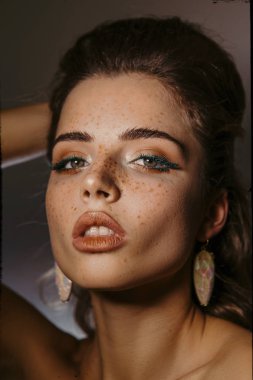 Güzellik portre makyaj, hacimli saç modeli ve küpeler ile bir güzel kız, kameraya bak