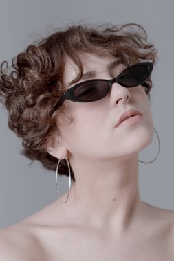 Kıvırcık saçlı, temiz cilt ve aksesuarları ile şık bir kız portresi