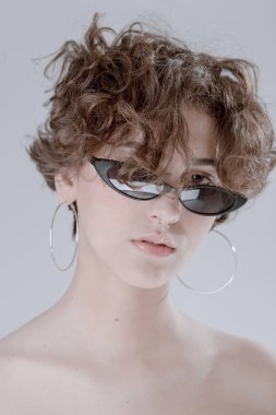 Kıvırcık saçlı, temiz cilt ve aksesuarları ile şık bir kız portresi