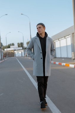 Şık giysiler içinde Yakışıklı adam gün batımında bir şehir caddesinde yürüyor