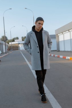 Şık giysiler içinde Yakışıklı adam gün batımında bir şehir caddesinde yürüyor