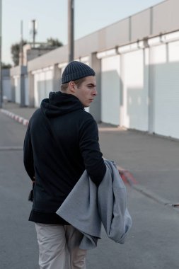 Şık giysiler içinde Yakışıklı adam gün batımında bir şehir caddesinde yürüyor